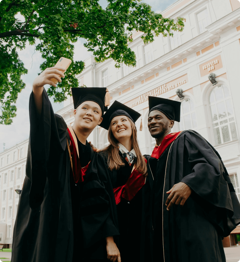 Newly graduated student wearing cap and gown taking group picture